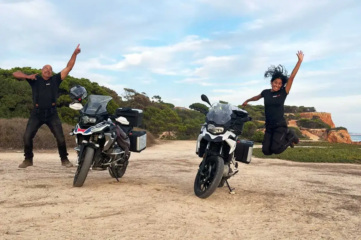 Dw&oacute;ch motocyklist&oacute;w, każdy z motocyklem 500 cm3, skacze z radości na tle malowniczego krajobrazu.