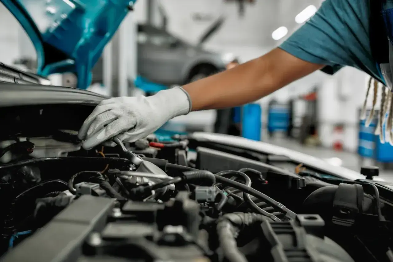 Mechanik w białej rękawiczce naprawia silnik diesla, szukając objawów uszkodzonego czujnika ciśnienia paliwa.