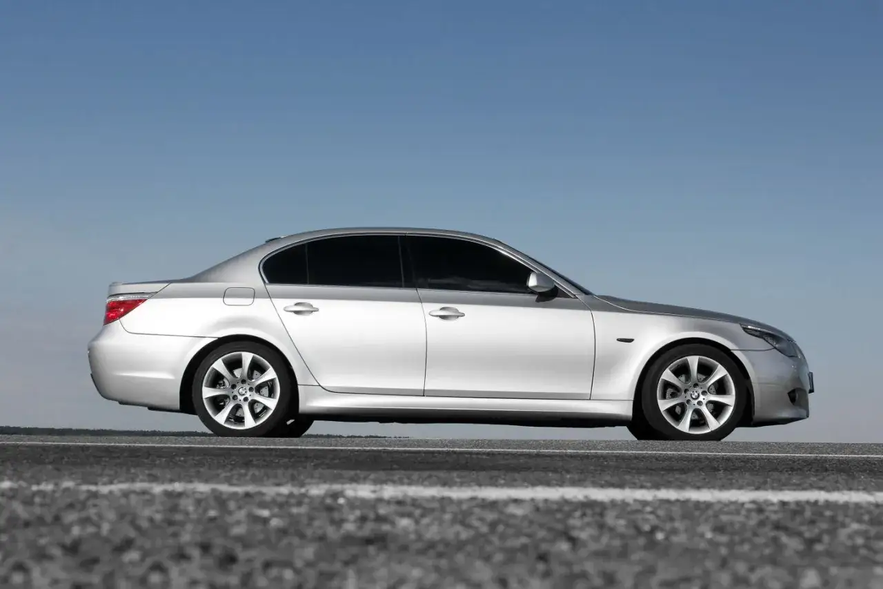 Srebrne BMW E60 535d na tle błękitnego nieba, zaparkowane na drodze.