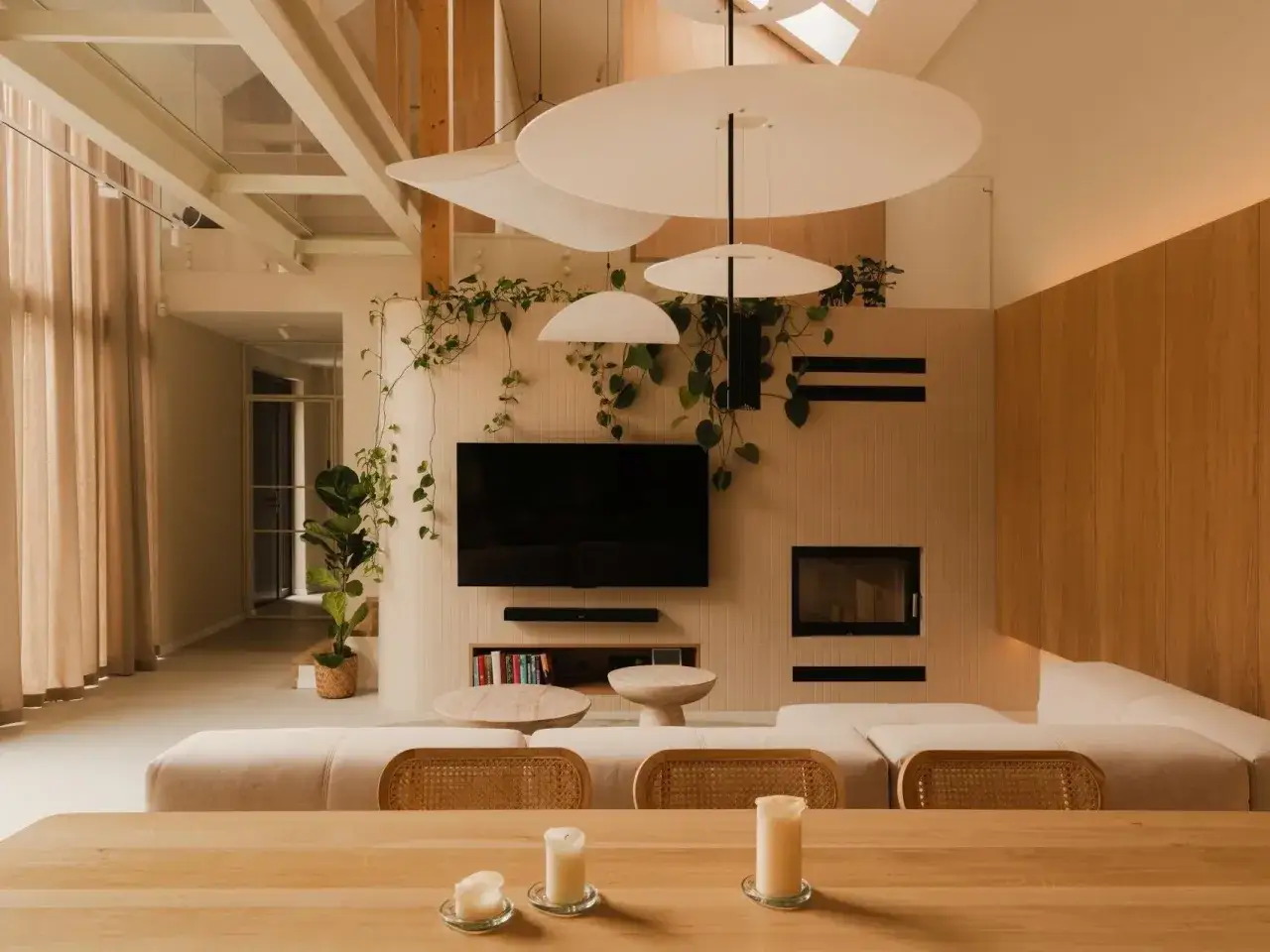 Jasne, przestronne wnętrze z kominkiem, telewizorem i wygodną kanapą. Doświetlenie pomieszczeń światłem naturalnym podkreśla ciepło drewna i roślin.