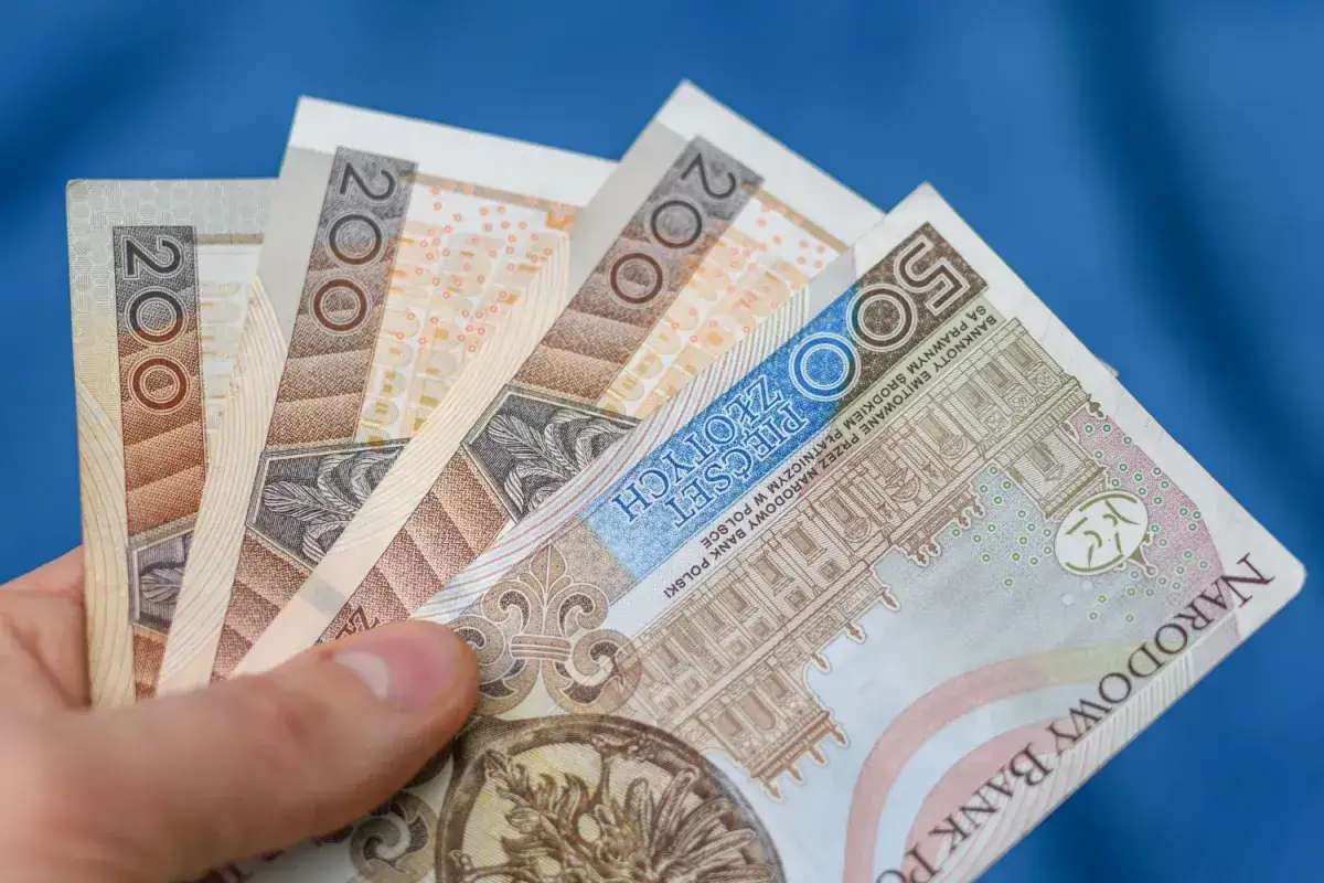 Dłoń trzyma polskie banknoty 200 i 500 zł. Zastanawiasz się, ile wynosi podatek belki od lokat?