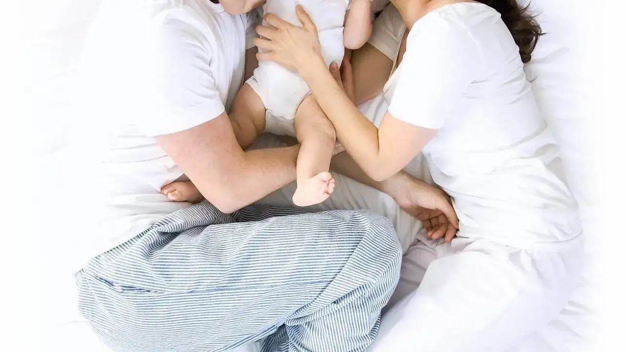 Rodzice z rocznym dzieckiem w łóżku, zamyśleni, ale spokojni