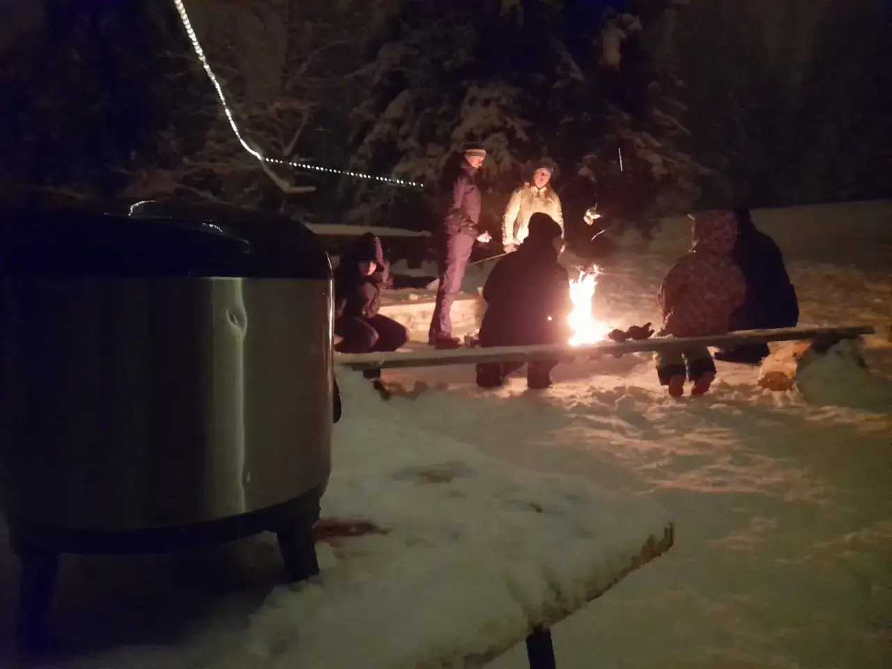 Nocny kulig w Bukowinie Tatrzańskiej. Grupa ludzi siedzi przy ognisku, ogrzewając się w zimową noc.
