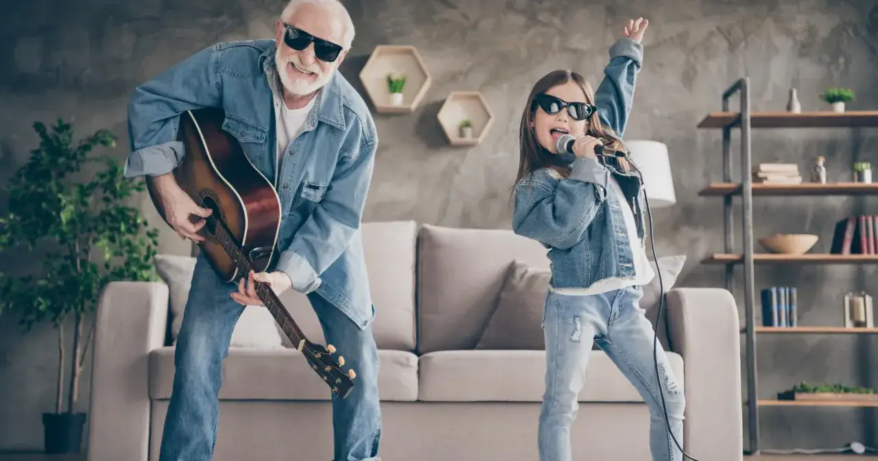 Dziadek gra na gitarze, wnuczka śpiewa do mikrofonu. Świetne pomysły na gry w domu dla całej rodziny.