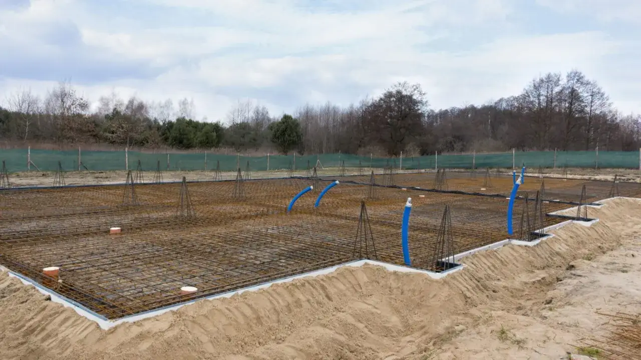 Siatka zbrojeniowa i rury na budowie fundamentów. Wybór odpowiedni jaki beton na fundament zapewni trwałość konstrukcji.
