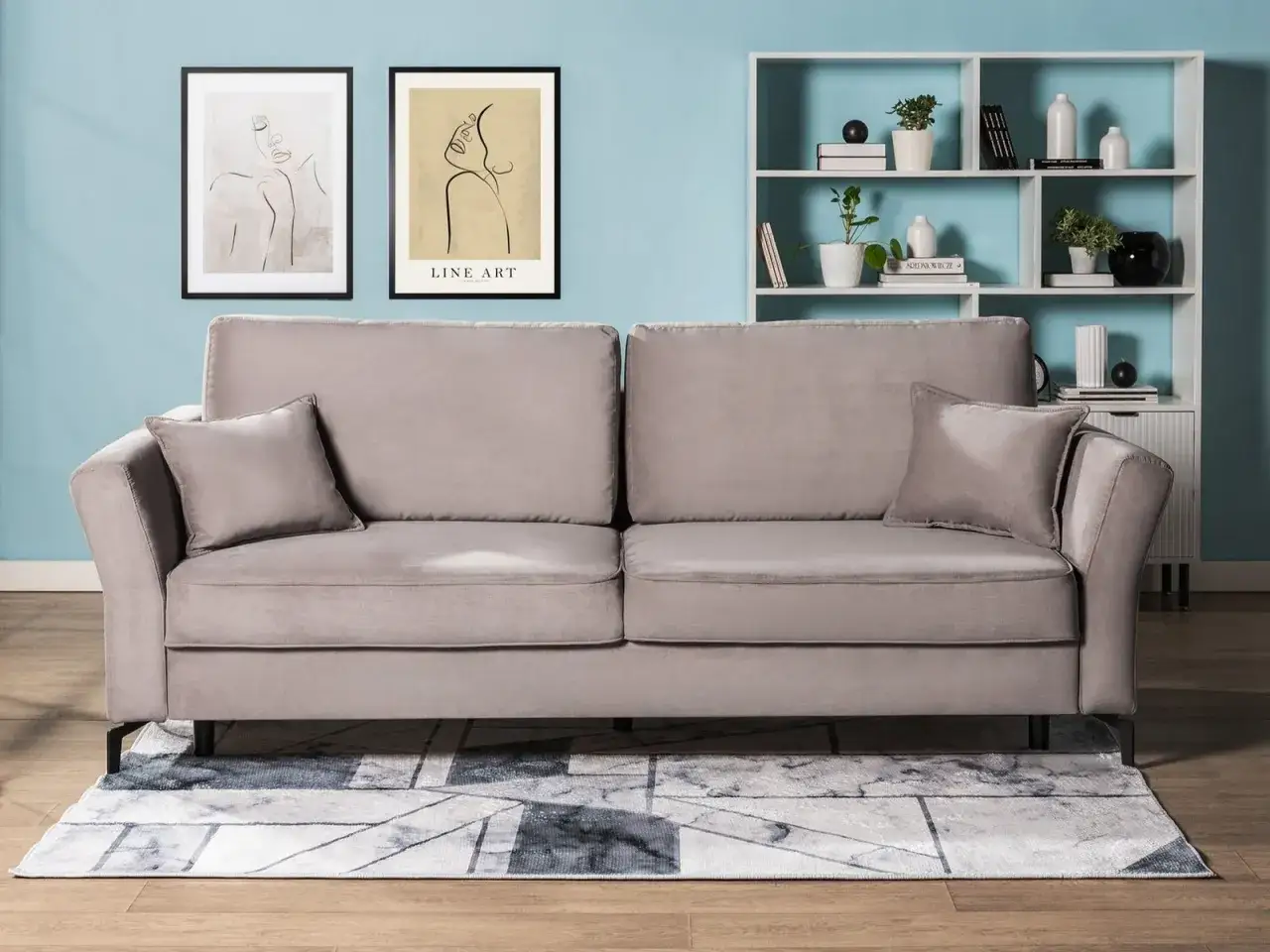 Szara sofa z poduszkami, obok dwa plakaty z rysunkami. Czy to sofa czy kanapa? Zależy od wielkości i funkcji, ale ta jest idealna do salonu.