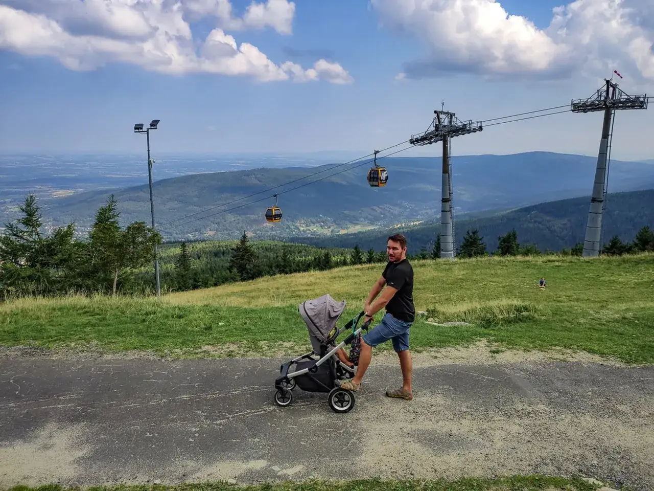 Spacer po g&oacute;rach z w&oacute;zkiem, w tle kolejka gondolowa i piękny widok na st&oacute;g izerski.