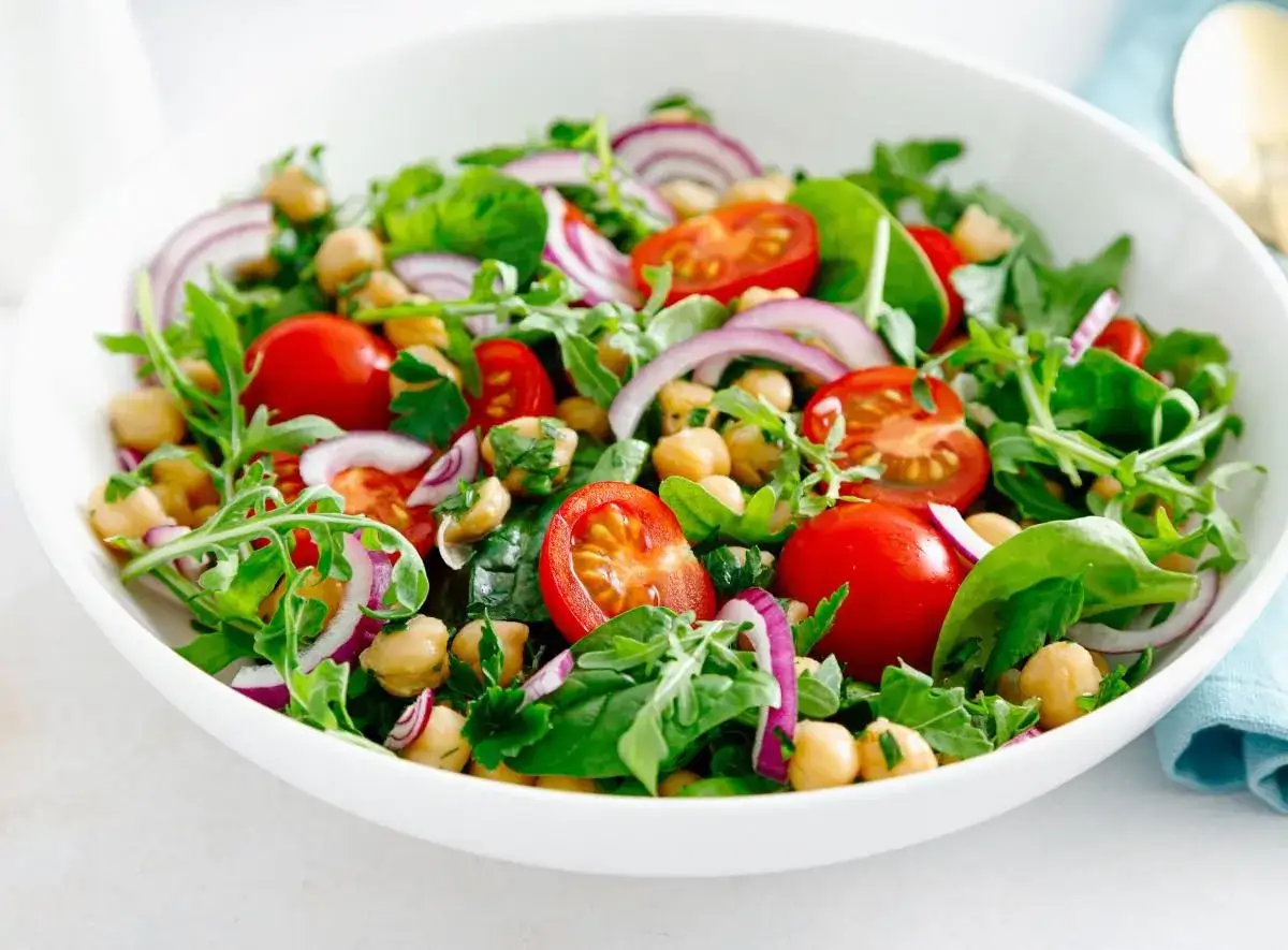 Kolorowa sałatka z ciecierzycą, pomidorkami, rukolą i czerwoną cebulą. Idealny przepis na zdrową sałatkę.