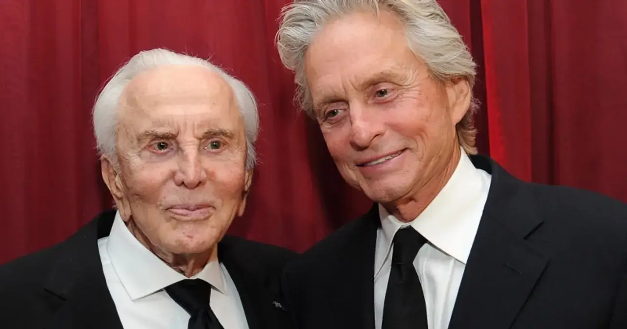 Kirk Douglas i jego syn Michael Douglas, dumny z polskie korzenie, na tle czerwonej kurtyny.