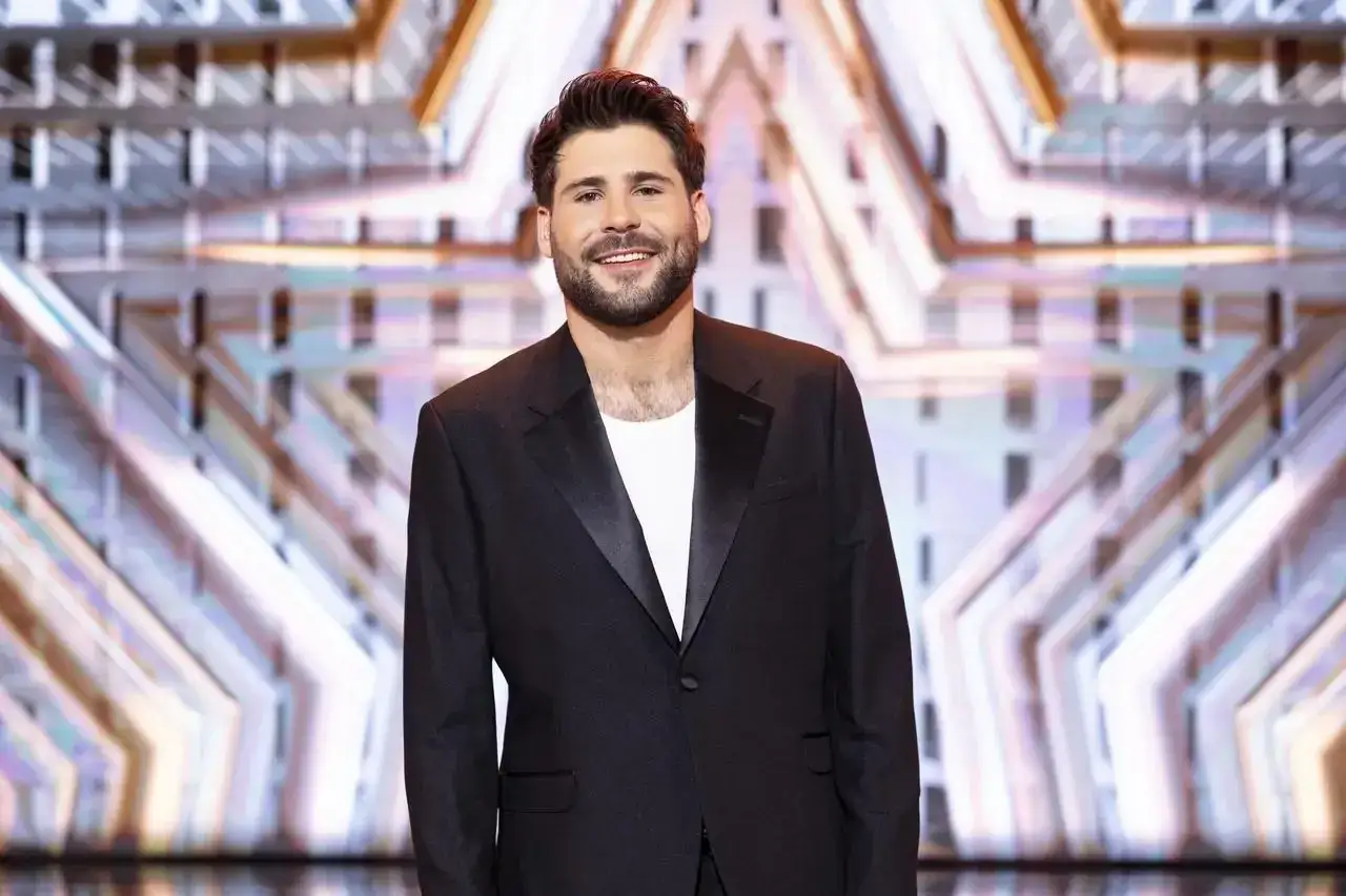 Uśmiechnięty Jan Pirowski w czarnym garniturze, z brodą. Może właśnie opowiada o swojej żonie.