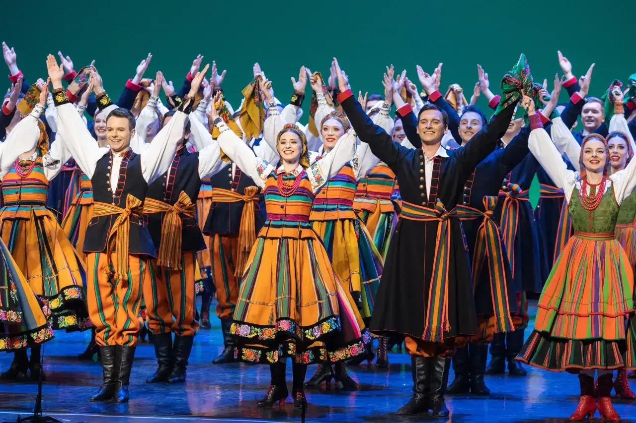 Zespół w barwnych strojach ludowych prezentuje muzyka ludowa mazowsza.