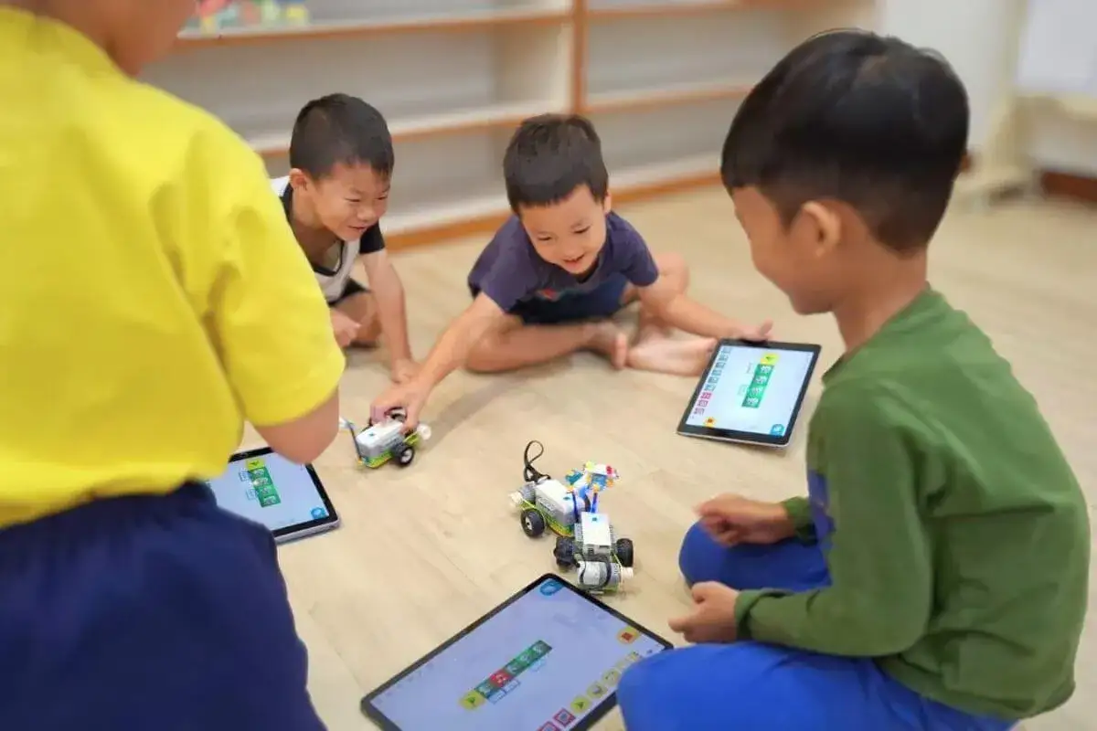 Dzieci z klasy 3 bawią się robotami i tabletami, ucząc się kodowania.