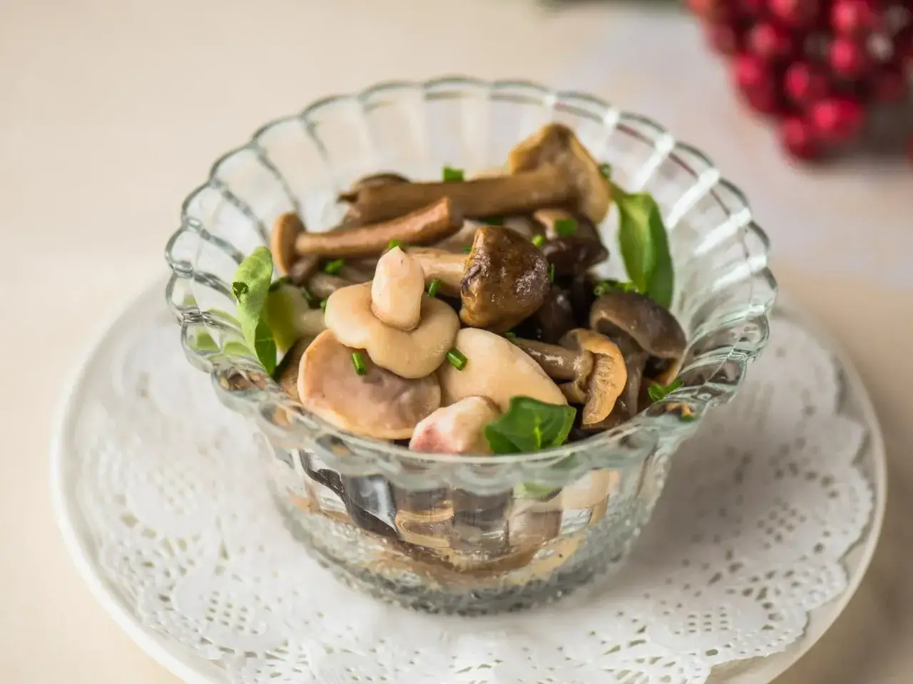 Pyszna sałatka z grzybkami marynowanymi, podana w szklanej miseczce, ozdobiona świeżymi ziołami.