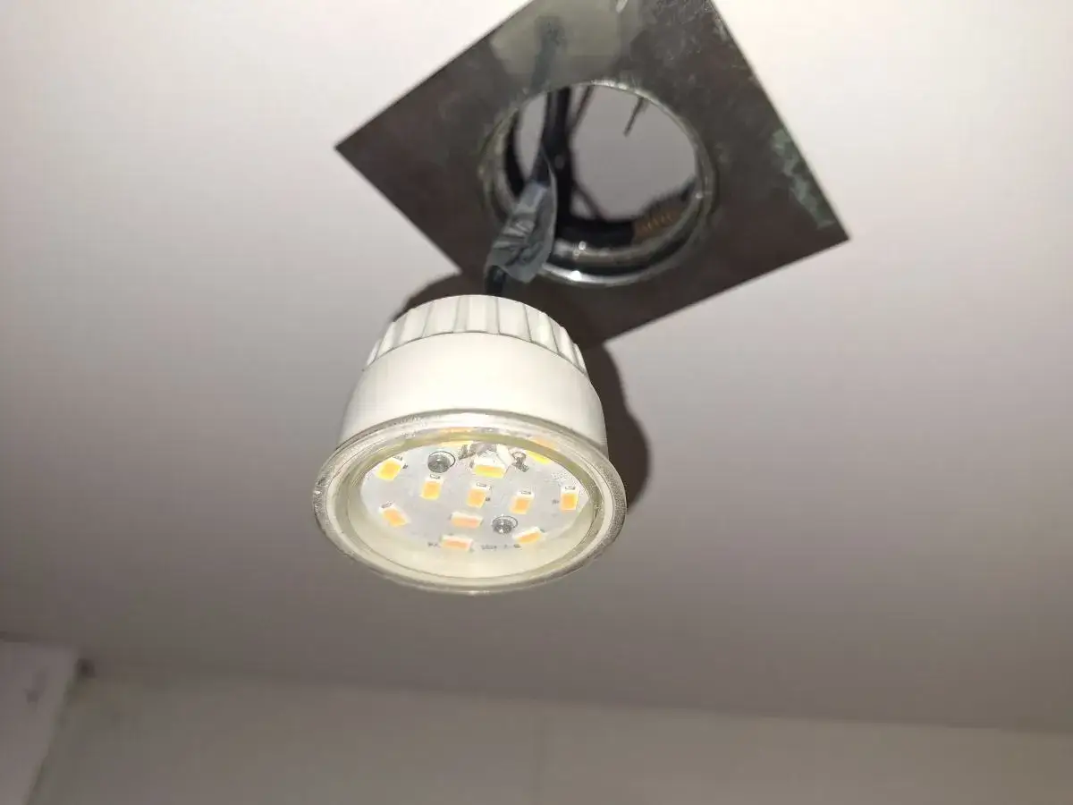 Jak wyjąć żar&oacute;wkę LED z oprawki sufitowej. Widoczna jest częściowo wyjęta żar&oacute;wka LED z widocznymi diodami.