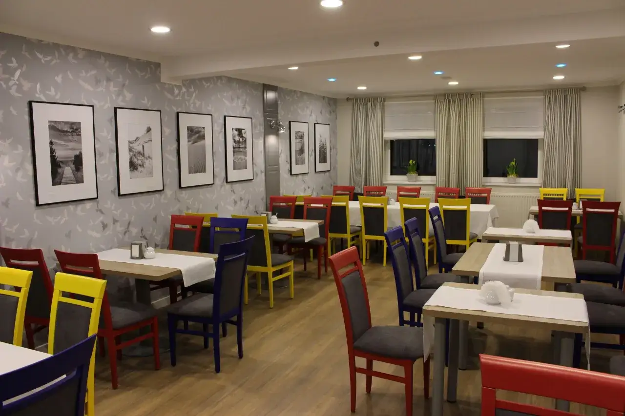 Jadalnia w hotelu La Siesta z kolorowymi krzesłami i tapetą w ptaki.
