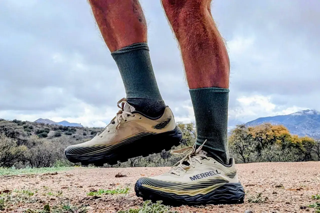 Beige buty trailowe Merrell z czarną podeszwą, gotowe na g&oacute;rskie wyzwania.
