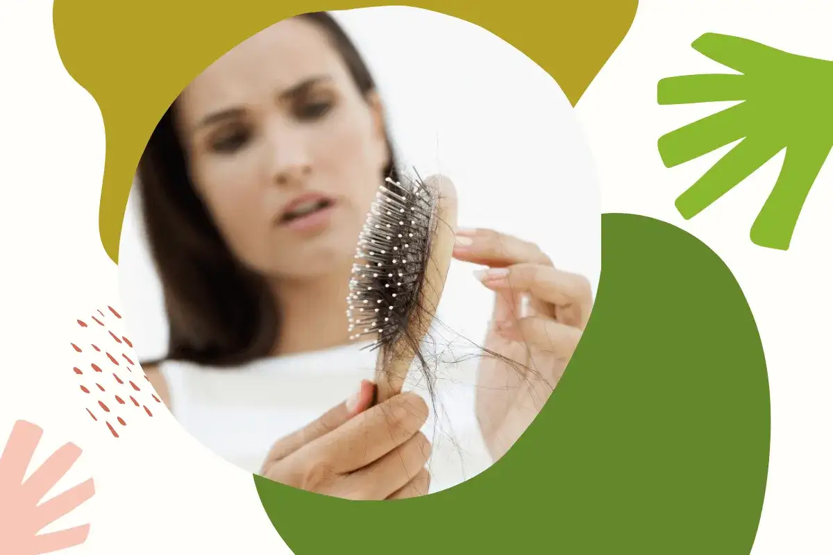 Zmartwiona kobieta trzyma szczotkę z garścią włosów. Szuka babcinych sposobów na wypadanie włosów.