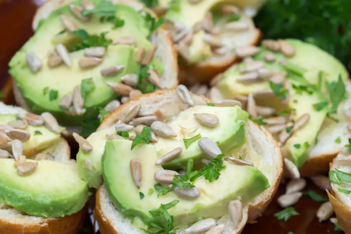 Pyszne kanapki na imprezę z awokado, pestkami słonecznika i natką pietruszki. Idealne na przekąskę.