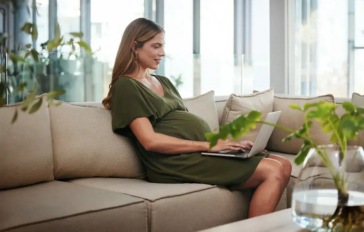 kobieta w ciąży z laptopem wypełnia wniosek online