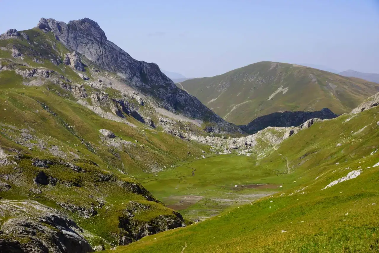 Zielone, skaliste albania g&oacute;ry z doliną i strumieniem.