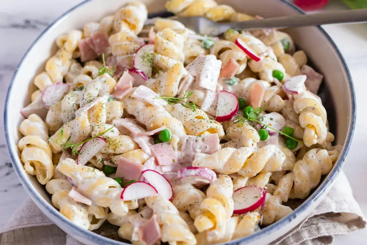 Sałatka z makaronem fusilli, szynką, groszkiem i rzodkiewką w kremowym sosie. Idealna na szybki obiad, czy to fusilli czy penne.