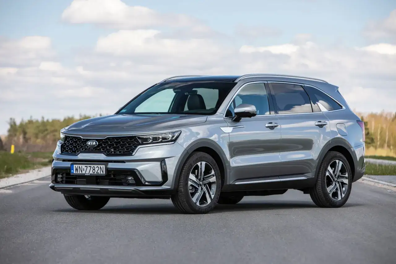 Szary Kia Sorento na drodze, z chmurami na niebie. Poznaj jego imponujące kia sorento wymiary i możliwości.