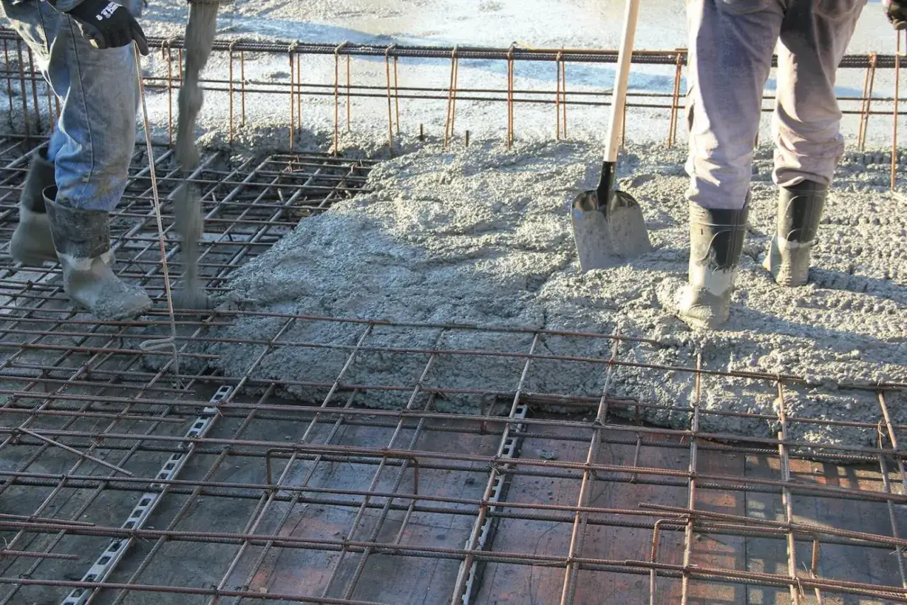 Wylewanie betonu na zbrojenie stropu. Widać pracowników w gumowcach i łopatę. Jaki beton na strop?