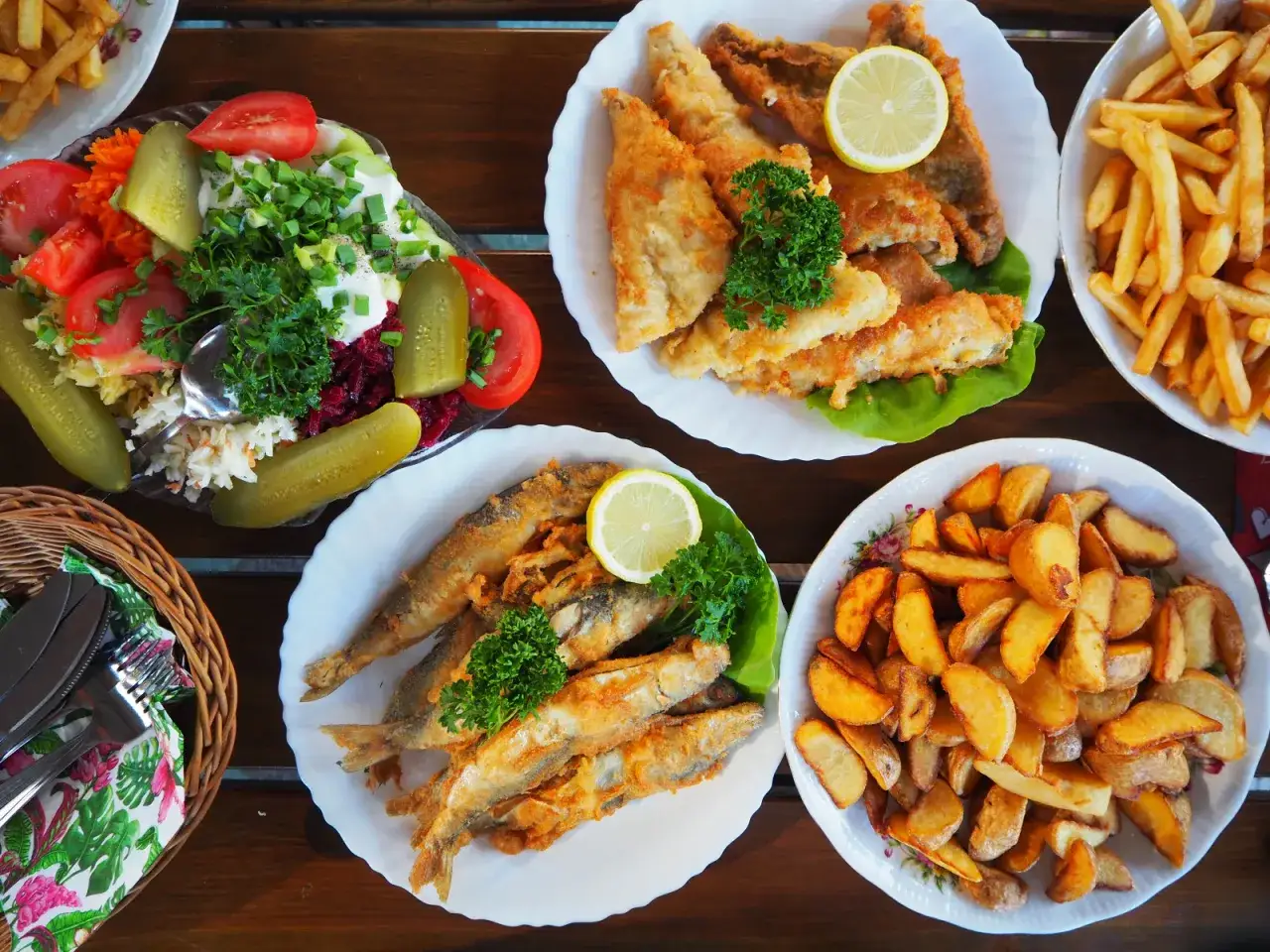 Szukasz miejsca, gdzie dobrze zjeść w Giżycku? Na stole smażona ryba, frytki, ziemniaki i świeża sałatka. Smacznego!