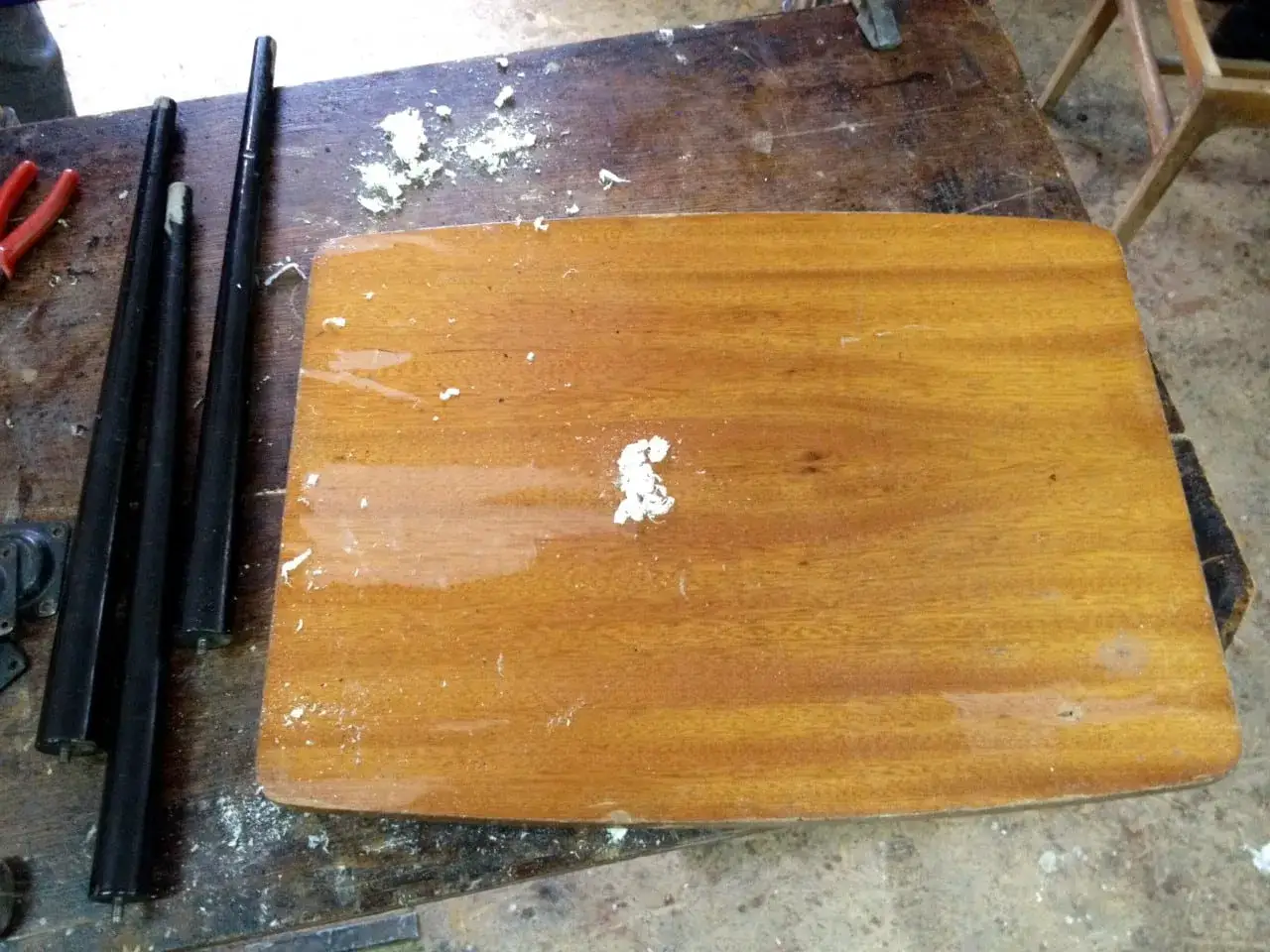 Drewniany blat i nogi mebli na stole warsztatowym, przygotowane do renowacji. Widać ślady po pracy, jak usunąć lakier z drewna.