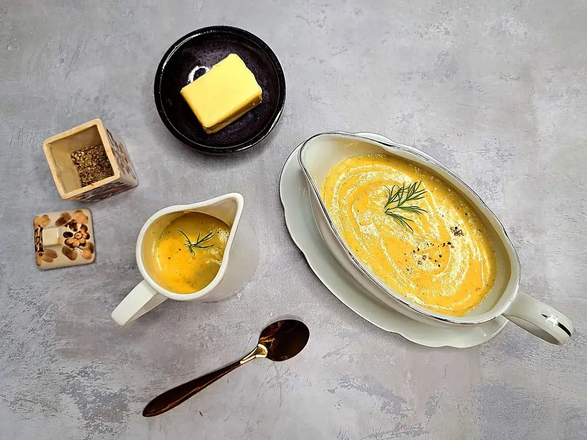 Aksamitny sos musztardowy z gałązką koperku, obok masło i przyprawy. Idealny do obiadu.