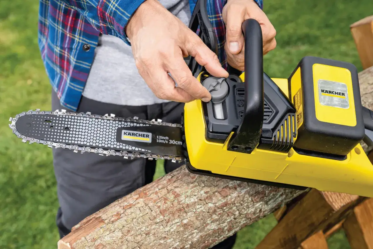 Ręce regulują napięcie łańcucha w żółtej pile Kärcher. Zastanawiasz się, jaką pilarkę spalinową wybrać?