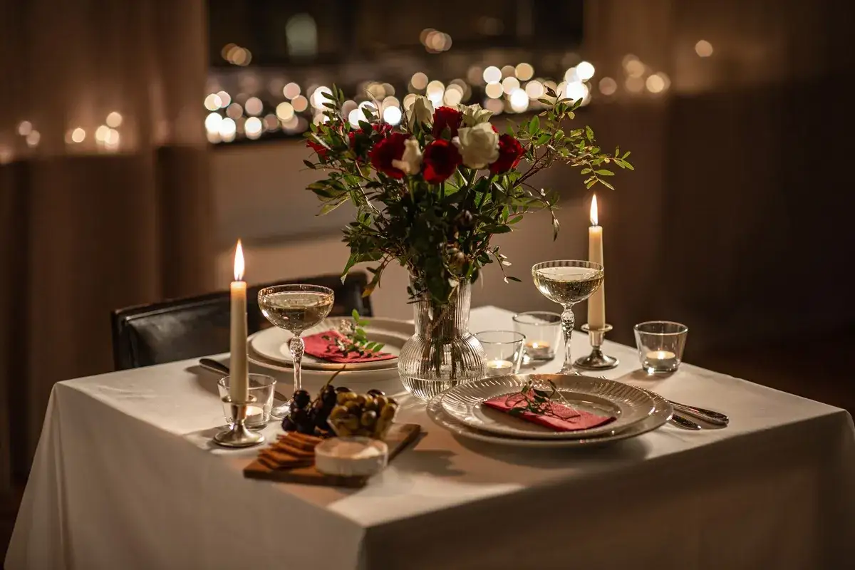 Stół nakryty na romantyczną kolację w domu. Świece, kwiaty i kieliszki tworzą nastrój. Co ugotować?