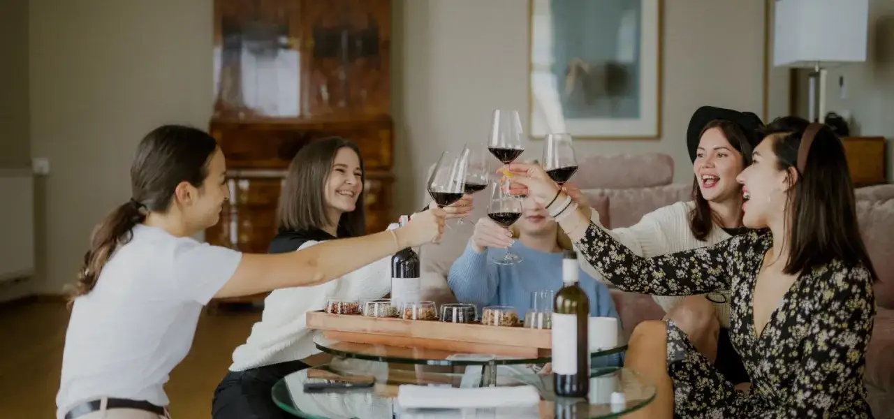 Przyjaciółki wznoszą toast kieliszkami czerwonego wina, celebrując wspólny weekend na Dzień Kobiet.