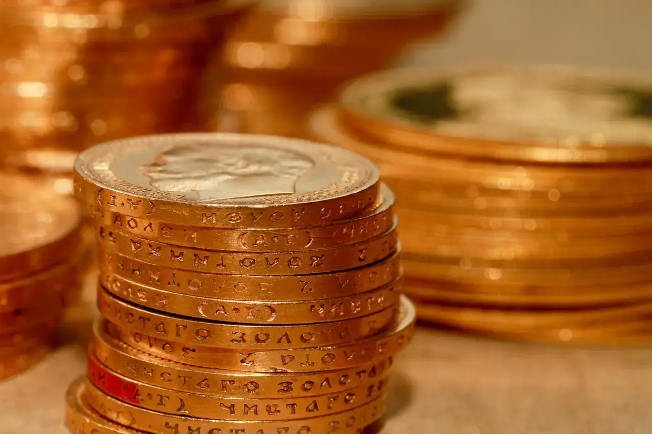 Stos złotych monet, idealnych do inwestycji. Zastanawiasz się, gdzie kupić złoto inwestycyjne? Oto odpowiedź w postaci błyszczących kruszców.