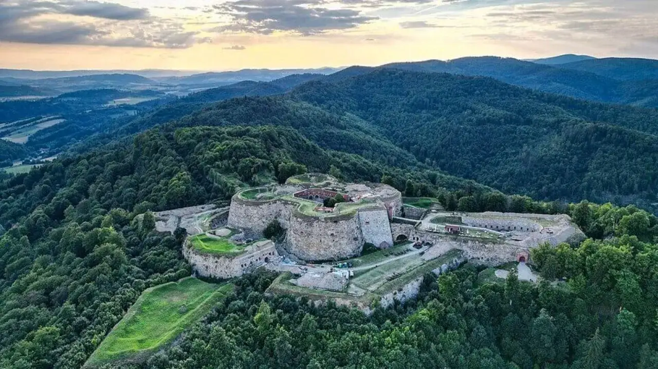 Twierdza na Srebrnej G&oacute;rze, imponujące atrakcje turystyczne w otoczeniu zielonych wzg&oacute;rz.