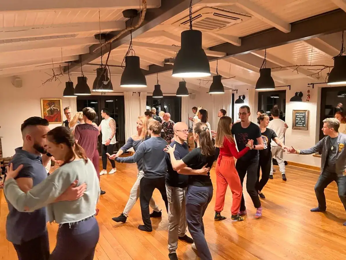 Ludzie tańczą bachata kroki nazwy. Widać pary w ruchu, instruktora i uczestnik&oacute;w lekcji tańca.