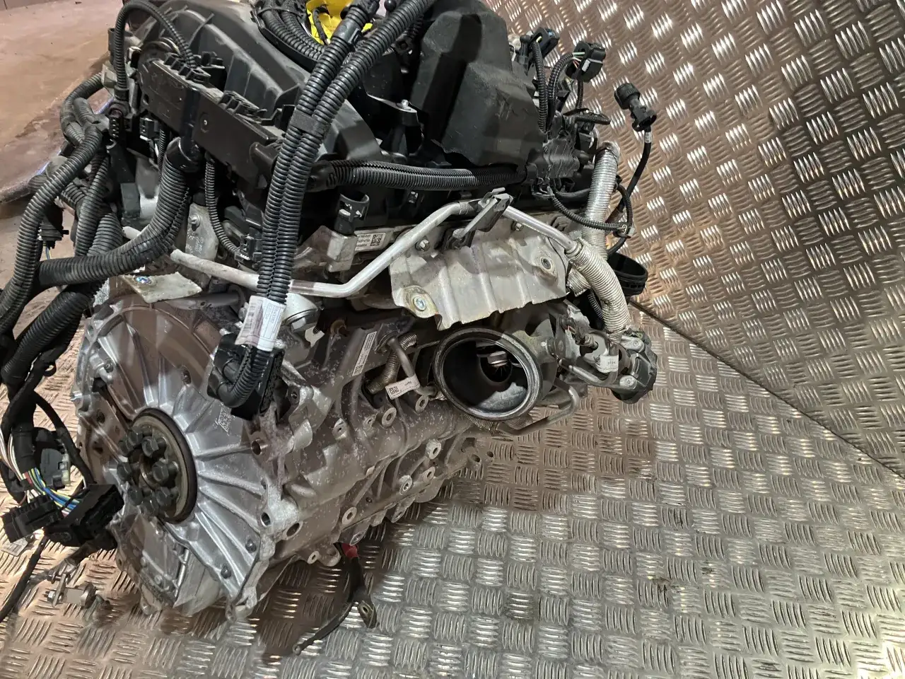 Silnik z BMW X1 F48, z widocznymi przewodami i elementami turbosprężarki, leży na metalowej powierzchni.