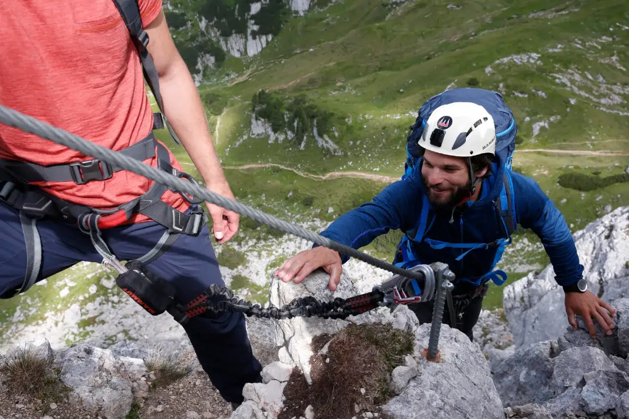 Wspinaczka po via ferrata to przygoda! Dw&oacute;ch mężczyzn pokonuje skalną trasę, zabezpieczonych linami.