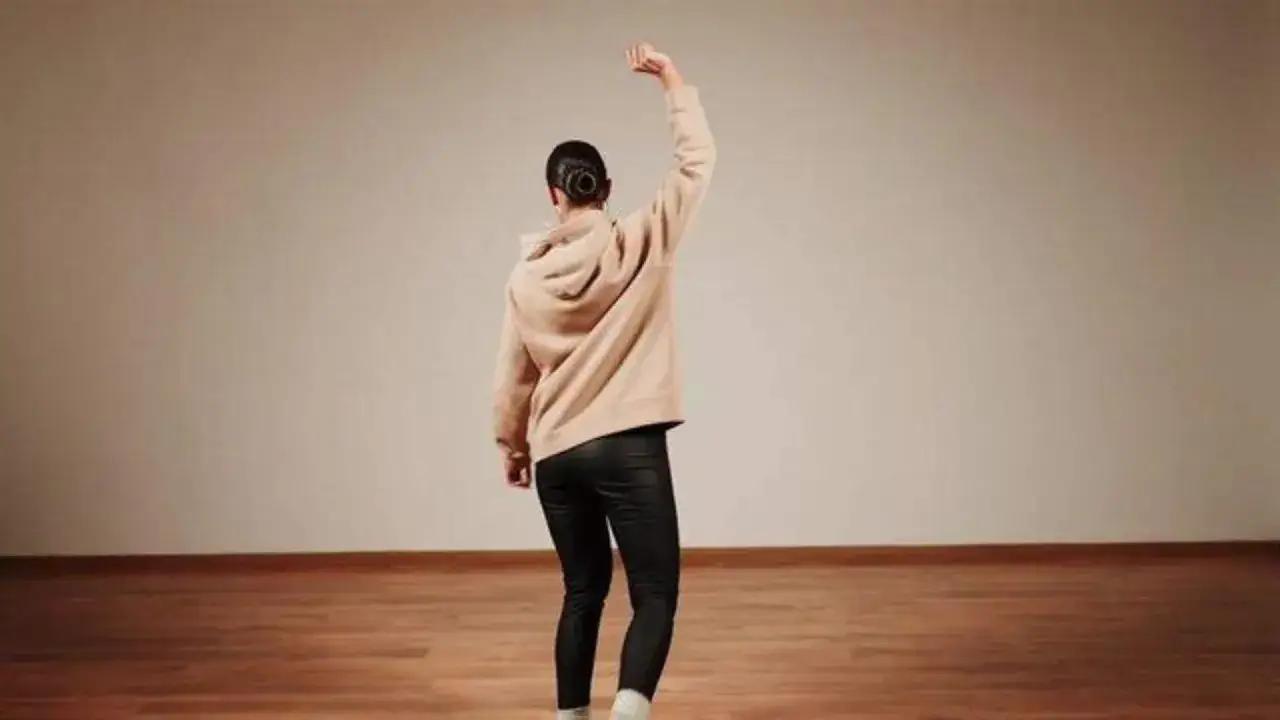 Tancerka w beżowej bluzie i czarnych legginsach wykonuje ruch, prezentując r&oacute;żne rodzaje tańca solo.