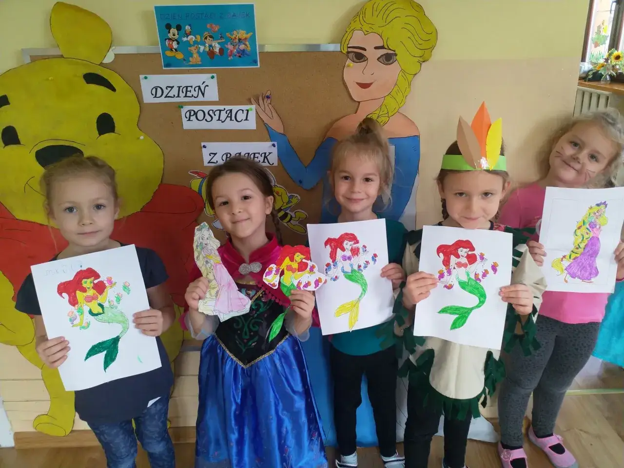 Dzień postaci z bajek scenariusz: dzieci prezentują rysunki Arielki i Roszpunki, ubrane jak księżniczki.