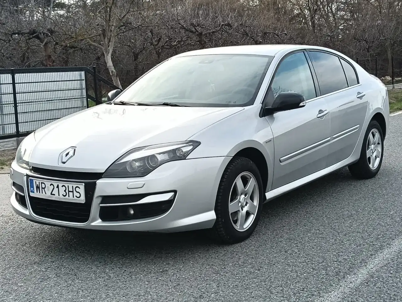 Srebrny Renault Laguna 3 z czarnymi lusterkami stoi na drodze.