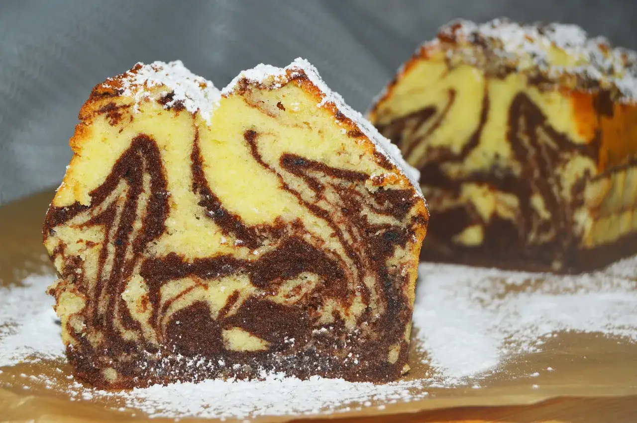 Wilgotna babka marmurkowa na oleju, opr&oacute;szona cukrem pudrem, kusi apetycznym wyglądem.