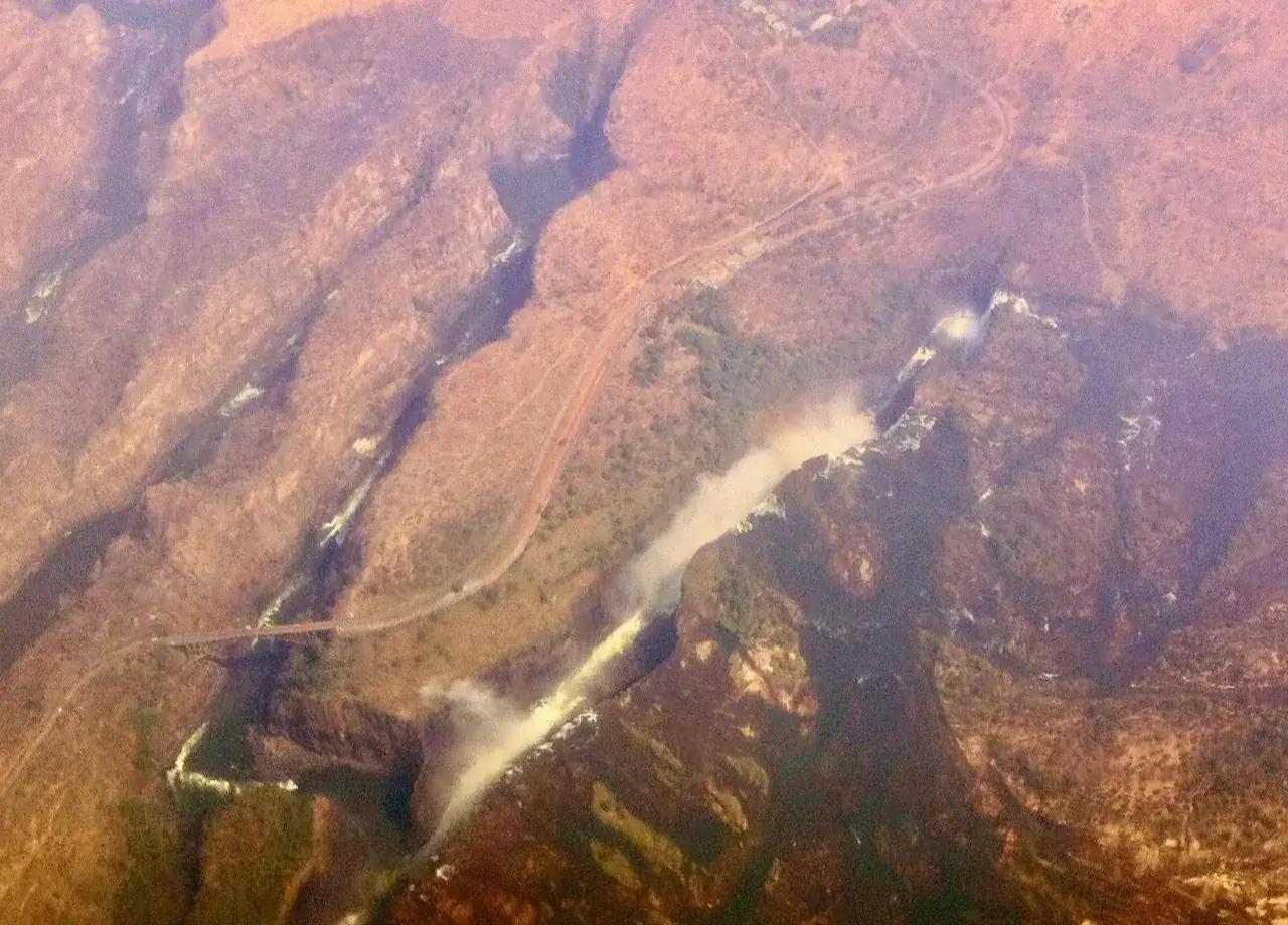 Widok z lotu ptaka na majestatyczne wodospady Wiktorii, z mgiełką unoszącą się nad kaskadami i wijącą się rzeką.