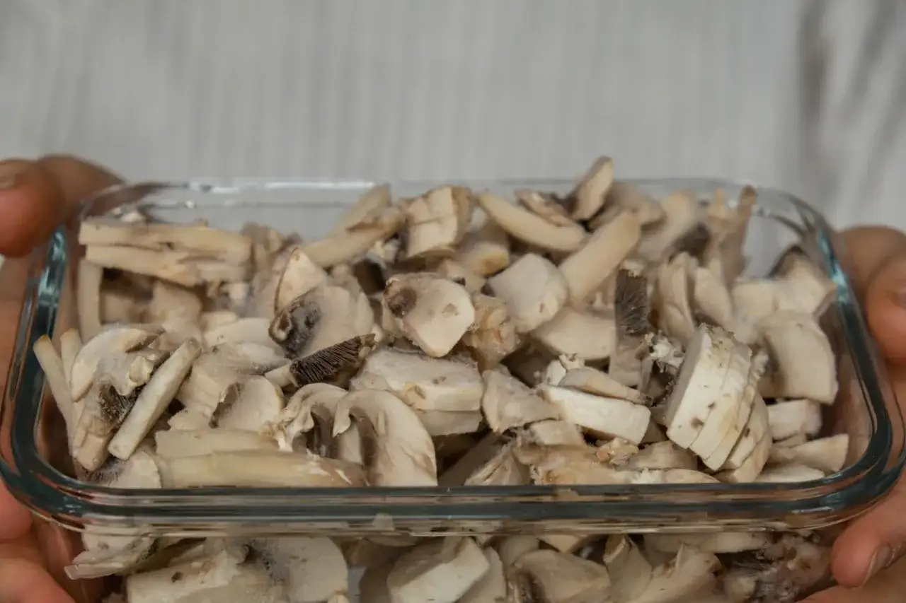 Pokrojone pieczarki w szklanym pojemniku, gotowe do mrożenia. Czy można mrozić pieczarki? Tak, to świetny sposób na ich przechowywanie.