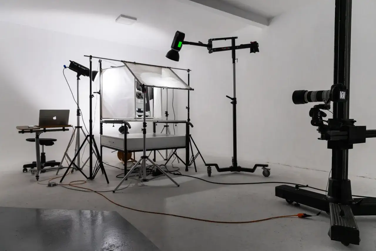 Studio do fotografii produktowej: jak zacząć? Sprzęt oświetleniowy, aparat na statywie i laptop do ustawień.