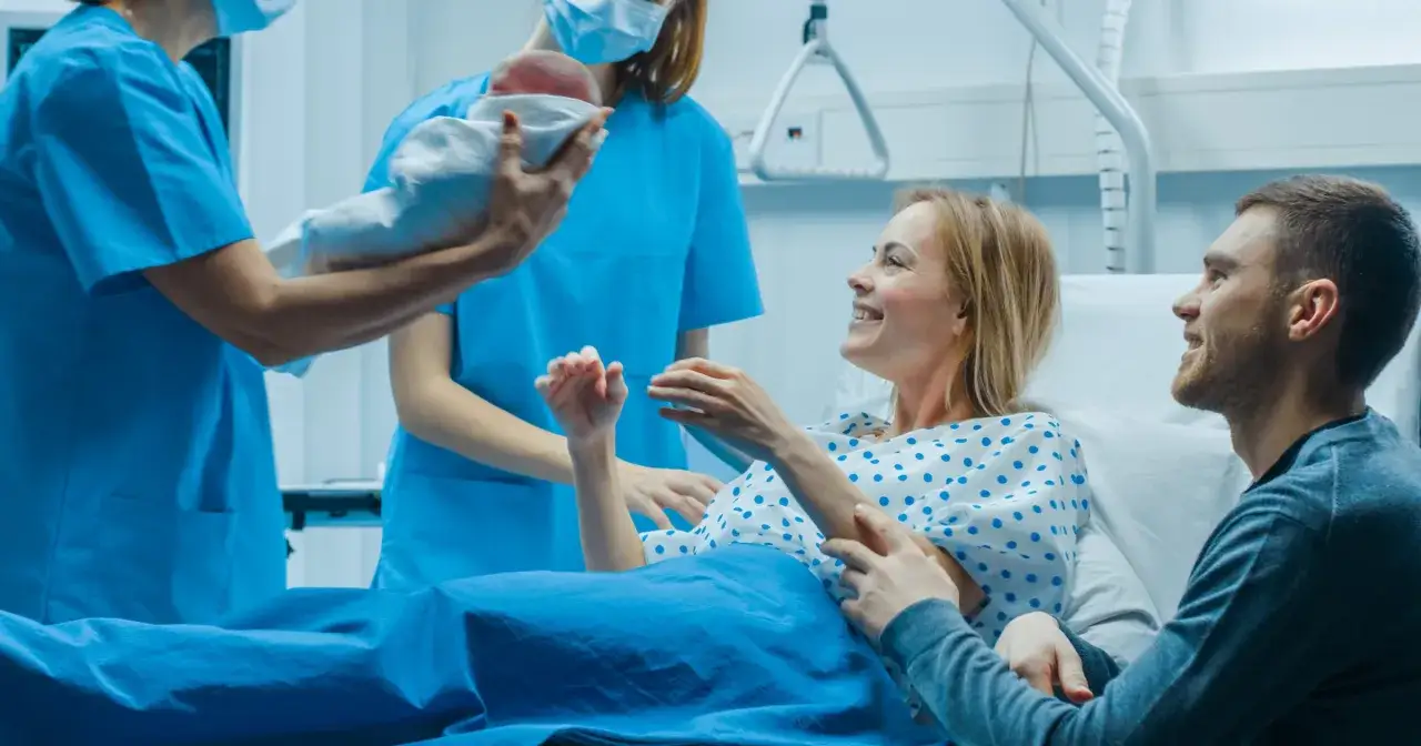 Szczęśliwi rodzice z noworodkiem w szpitalu. Warto mieć przygotowane pytania do położnej przed porodem, by czuć się pewniej.