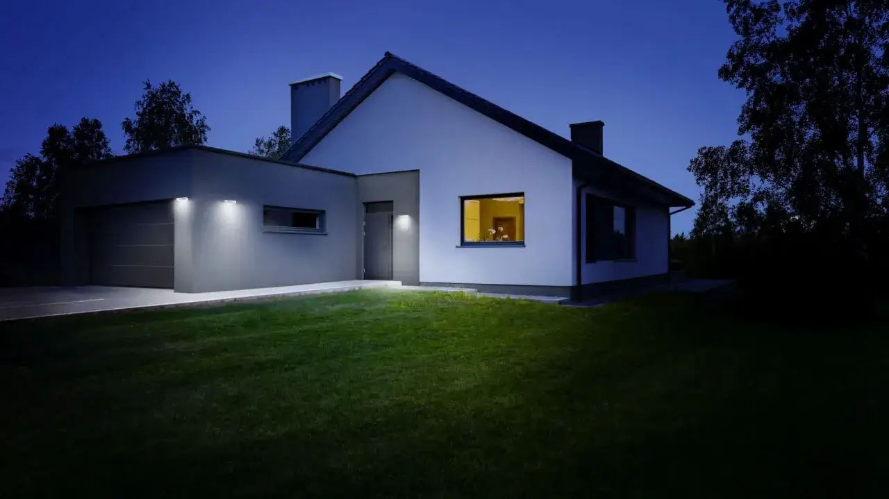 Nowoczesny dom z oświetleniem elewacji od dołu. Lampy podkreślają architekturę i tworzą przytulną atmosferę.