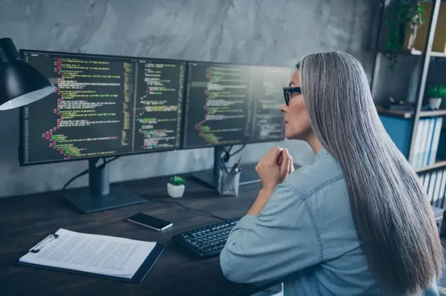 osoba pracująca na dw&oacute;ch monitorach, ergonomiczne stanowisko pracy