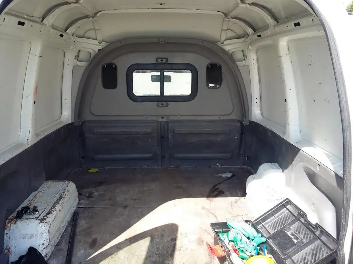 Pusta przestrzeń w samochodzie, idealna do przerobienia na minicamper. Widoczna skrzynka z narzędziami i schowek.