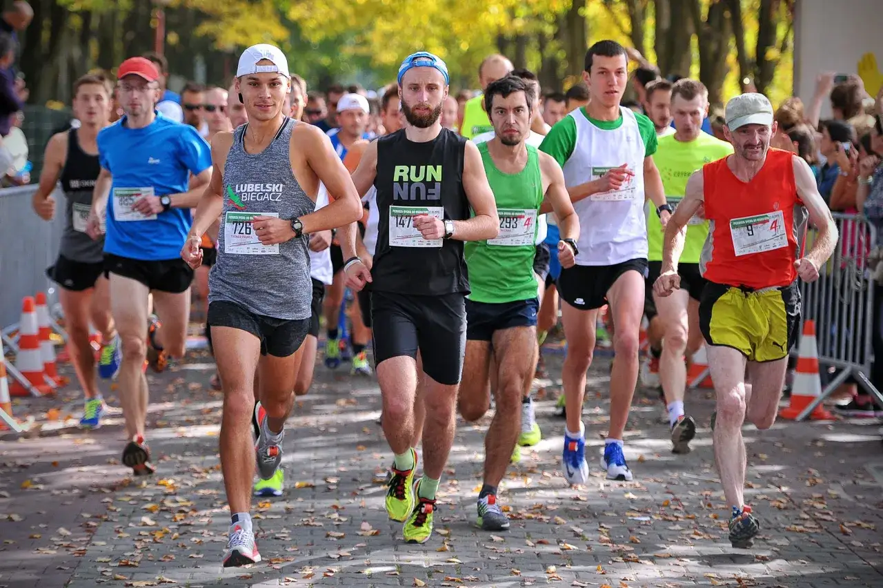 Biegacze w maratonie czas amatora, każdy walczy o swoje rekordy. Liście na chodniku dodają jesiennego klimatu.